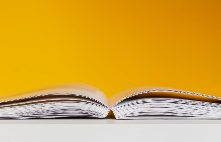 In an illustration, a textbook lays open on an empty table. UPrep teachers report student and family stressors on forms of assessment.