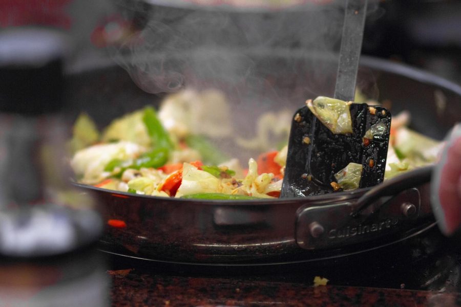 Person cooking food in a skillet. (Martin Lopez/Pexels)