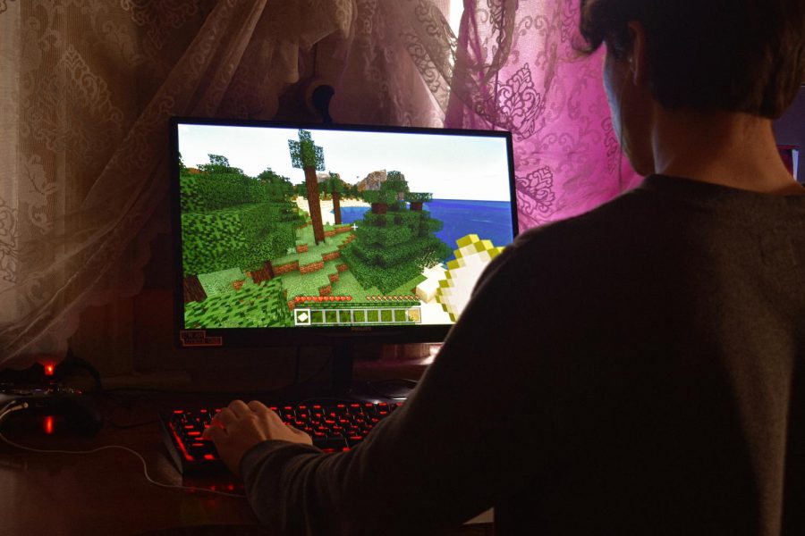 A man playing Minecraft in a dark room. (Alexander Kovalev/Pexels)