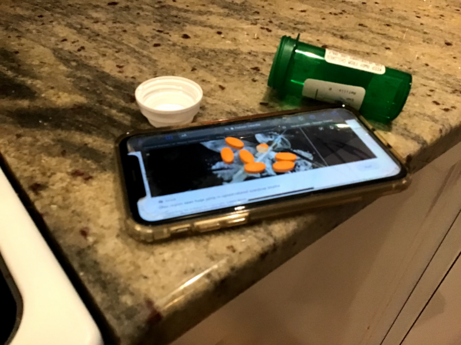 A spilled pill bottle is on top of a phone 