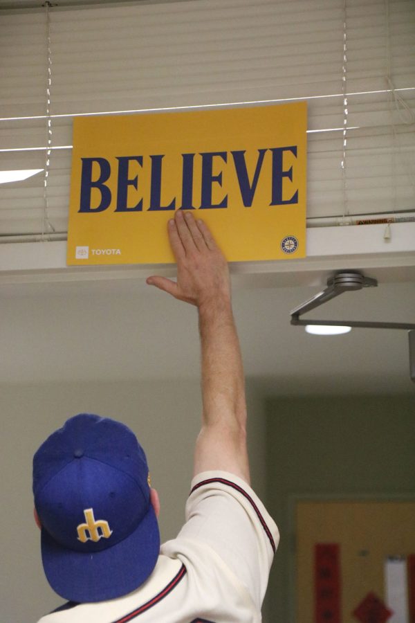 The BELIEVE sign was a symbol of hope for Mariners fans near the end of the 2021 season.
Strouse slaps the sign to
resemble the slap players
often do before games.