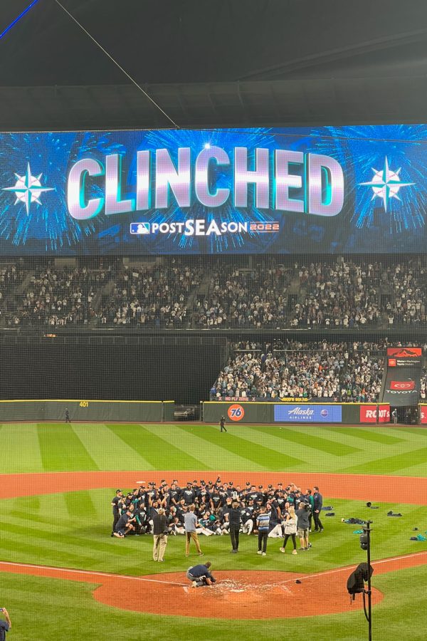 Mariners players and staff gather on the field for a photo after clinching the playoffs