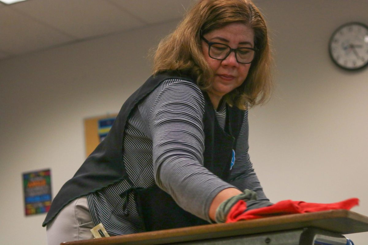Mirna Ruiz wipes off a desk in a math classroom. “On a typical day...after class, I come, I prepare things, I start in the first classroom on the third floor, and it is generally unoccupied,” Ruiz said.