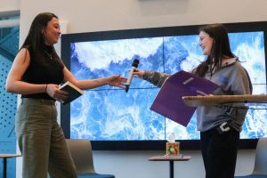 Wynne Johnson hands award-winning author Chanel Miller a microphone to read a portion of her book “Know My Name” written in 2019. They stand in front of an audience of students, speakers, parents and staff in UPrep’s newly built ULab.  