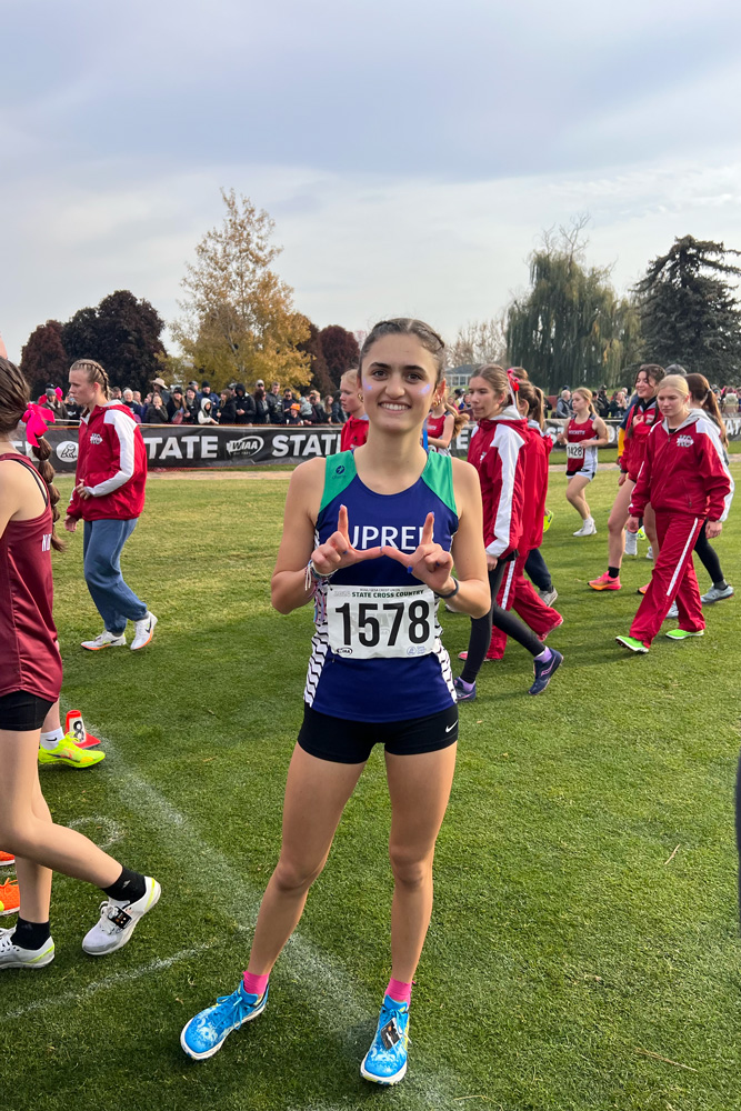 Junior Adeline Armato makes a "U" gesture signifying UPrep in Pasco, Washington moments before her race on Nov 9. Armato is the first girl from UPrep to compete in state since 2019. 