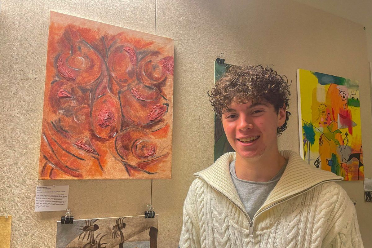 Junior Max Cook poses with his cubist art piece. "I made a still life out of these fake apples and fake mangoes, and these bowls and stuff," Cook said. "Then I made a cubist piece of that by looking at all these different perspectives. When I was painting it, I used this 3d medium... that was cool."