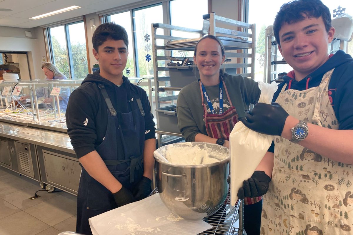 Ninth graders Gregor Schuchart, Zinedine Smith and teacher Kayla Robertson prepare frosting in the commons before lunch on January 9th.