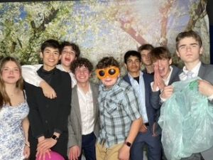 Students huddle in-front of the photo booth at Spring Fling. The dance was sparsely attended, so this group represents a large proportion of the attendees. 