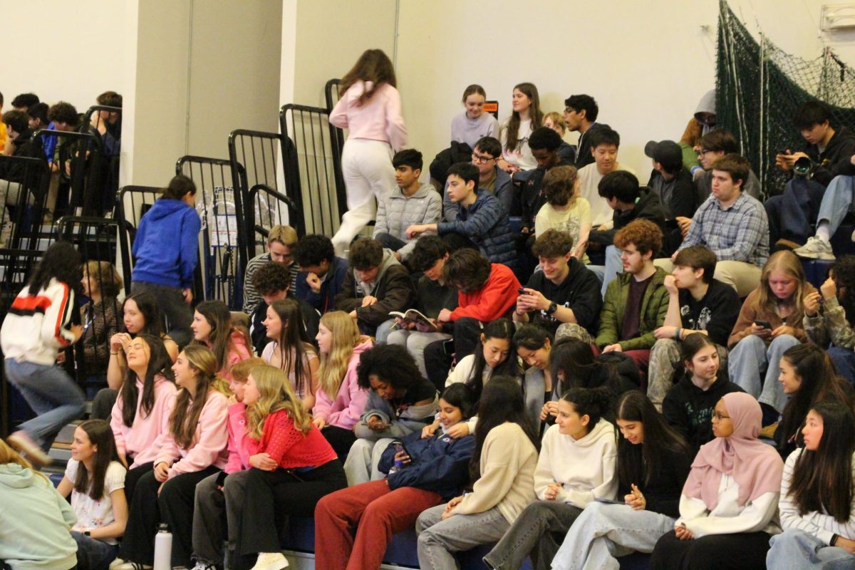 Students watch the performance and read and look at their phones during the dancing with the stars assembly.