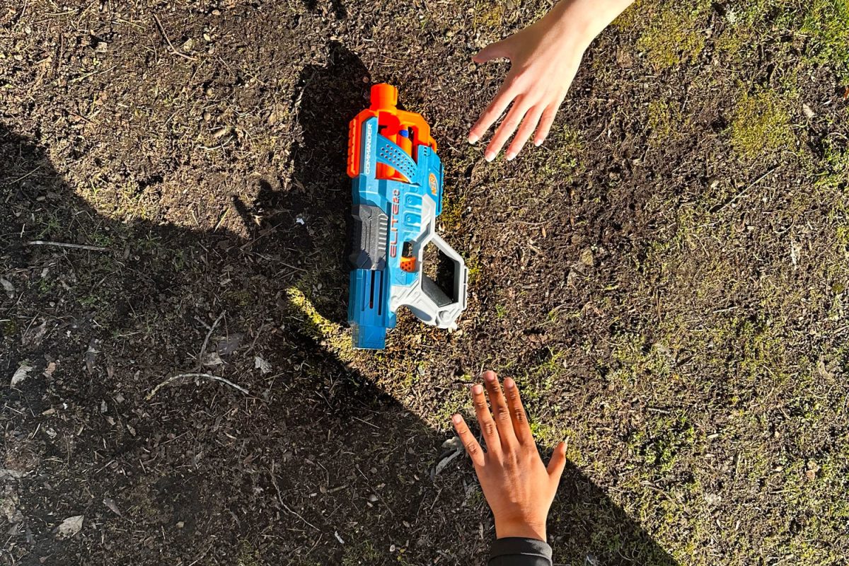 Two hands reach for a toy gun. 