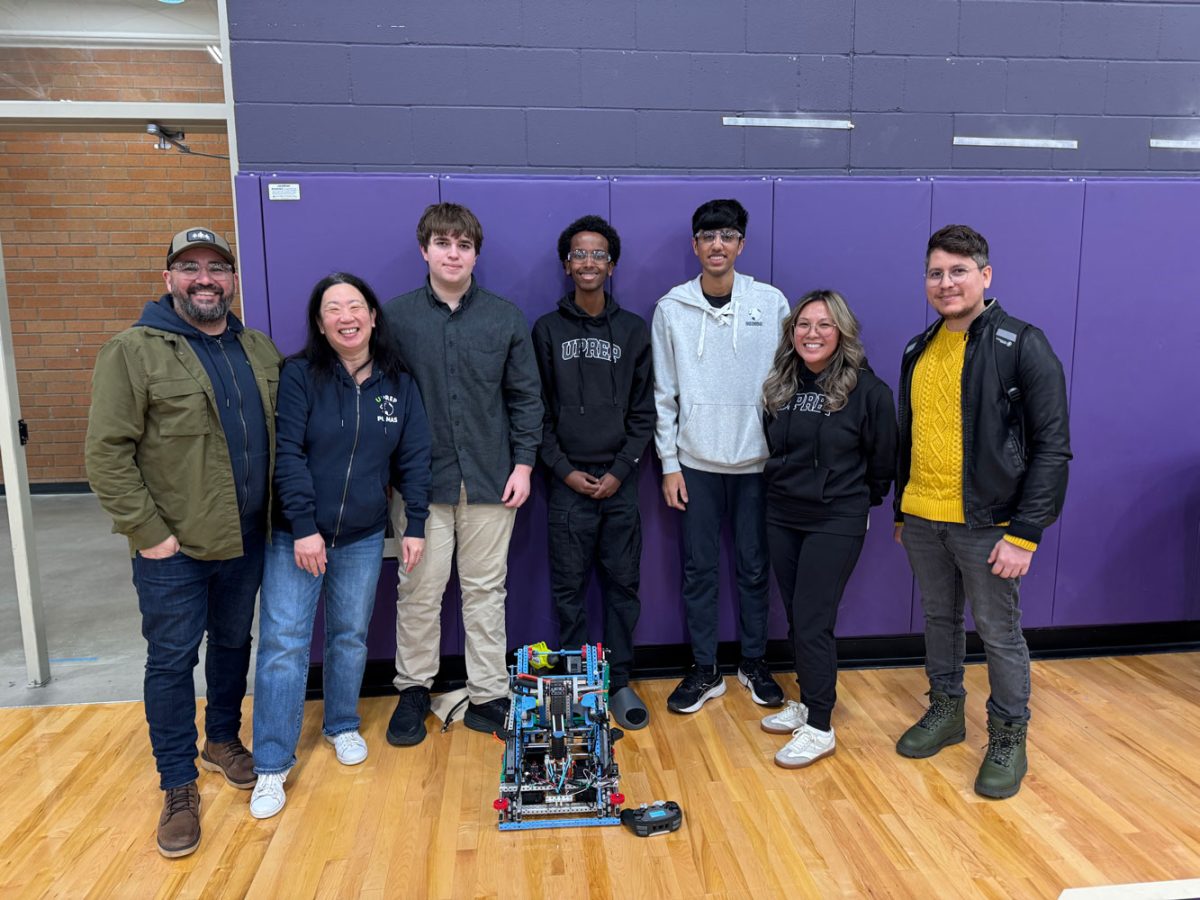 Robotics team members Ben Frischer, Mohamed Farah and Niam Patel stand with their robot alongside family and faculty members. 