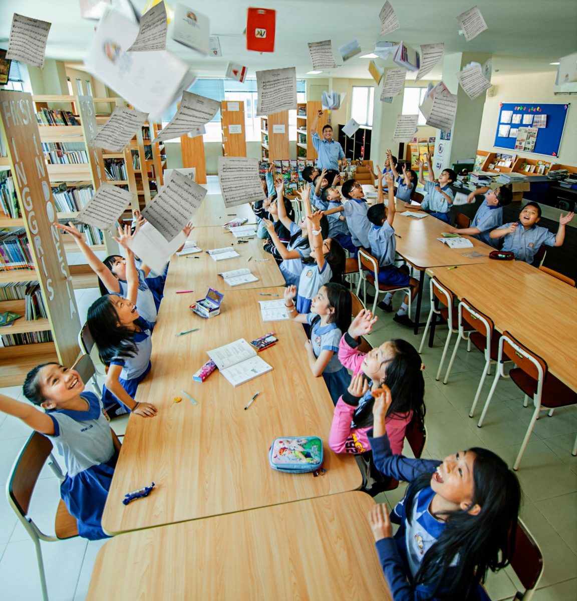 Students throw paper in a classroom.