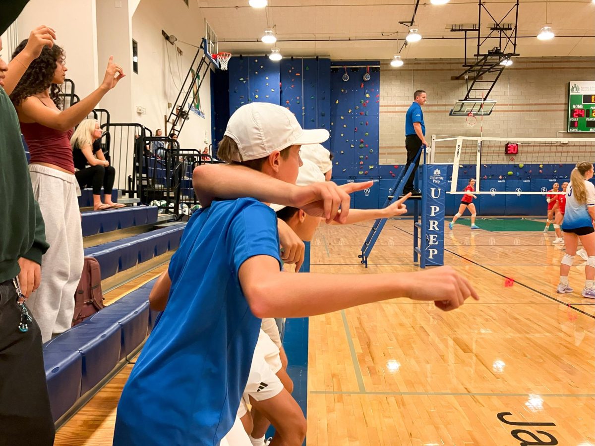 Juniors Will Madrid and Brandon Liu link arms with senior Owen Bradley to cheer on the Pumas during the third set of the team's 3-0 win against Seattle Christian.