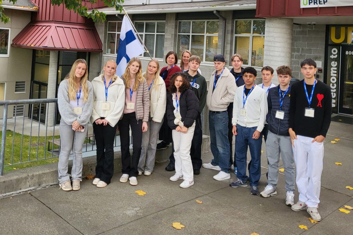 The 12 visiting Finnish students stand with their chaperones in front of the Finnish flag at UPrep's Main Entrance.