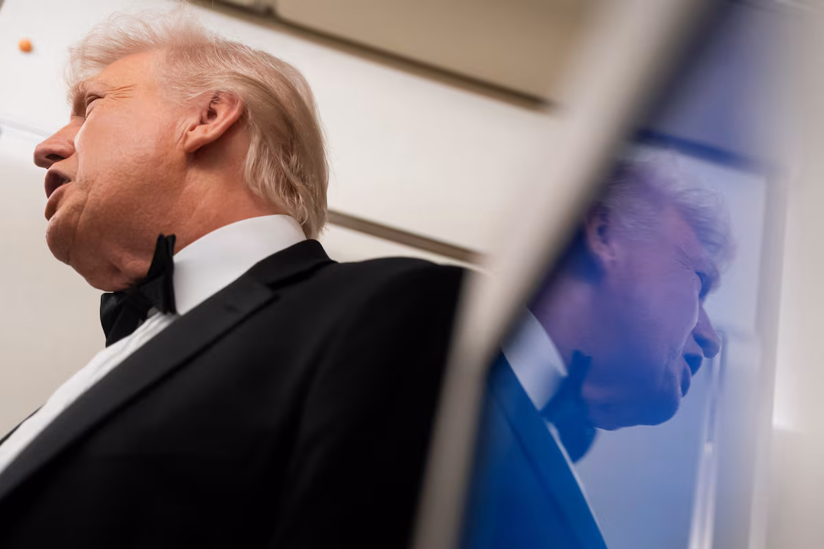 U.S. President Donald Trump is reflected in a television screen while speaking with members of the media on board Air Force One en route to Palm Beach, Florida, U.S., January 31, 2026. 
